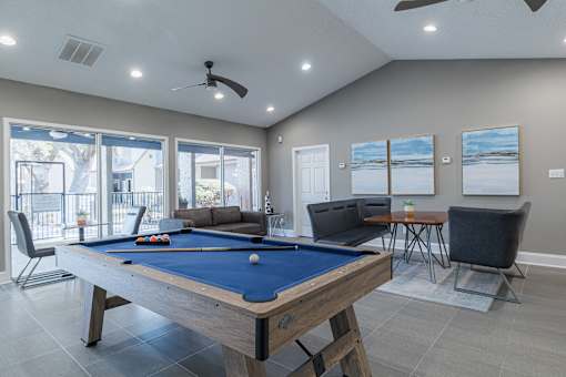 A pool table is in the middle of a room with a couch, chair, and television.