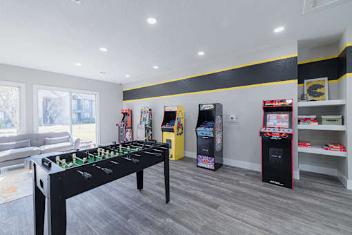 A foosball table is in the middle of a room with a couch and arcade games.