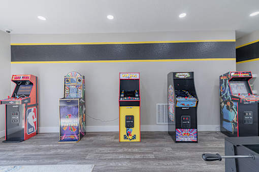 A row of arcade machines are lined up against a wall.