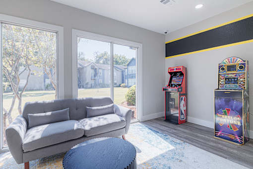 A grey couch sits in a living room with a vintage arcade machine.