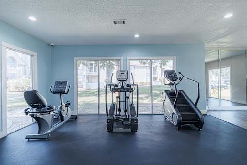 A spacious gym with a treadmill, elliptical trainer, and a stationary bike.