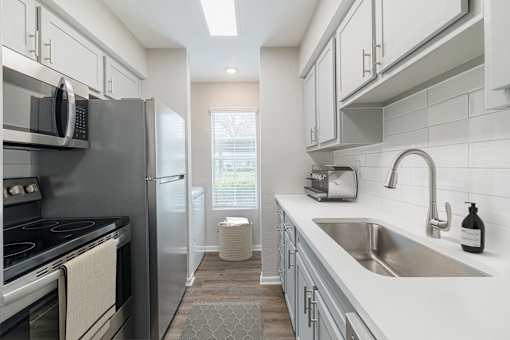 A modern kitchen with a stove, refrigerator, and sink.