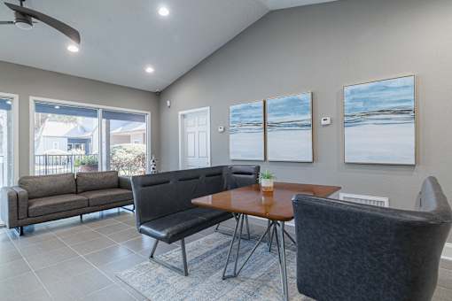 A living room with a grey couch, a black chair, and a brown table.