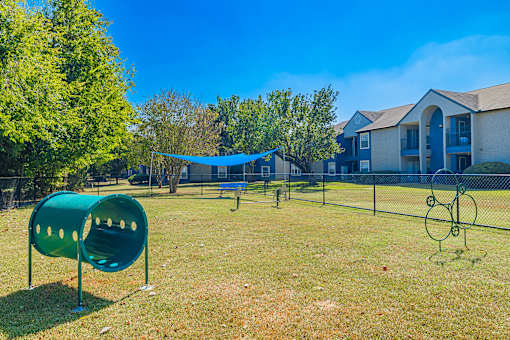 A playground with a green slide and a blue canopy.