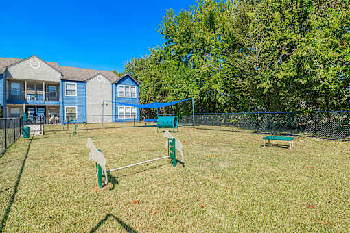 A dog park with a blue fence and a green bench.