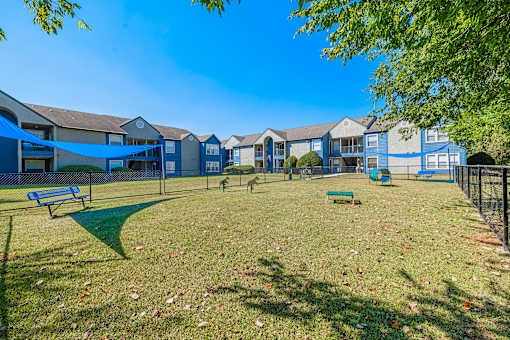 A sunny day at the park with a blue sky and apartment buildings in the background.
