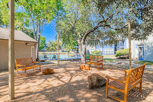 A park with wooden benches and trees.