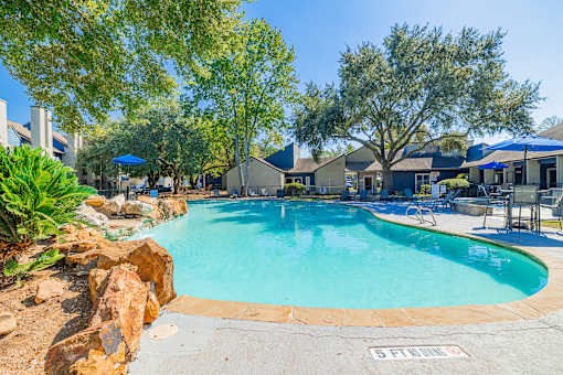 A swimming pool surrounded by trees and rocks.