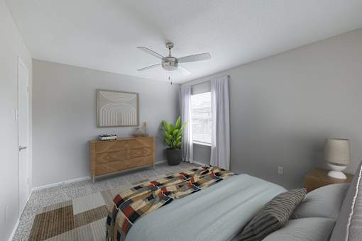 A bedroom with a bed, a dresser, a ceiling fan, and a window with a plant.