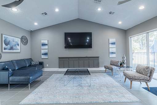 A living room with a blue sofa, a black coffee table, and a television mounted on the wall.