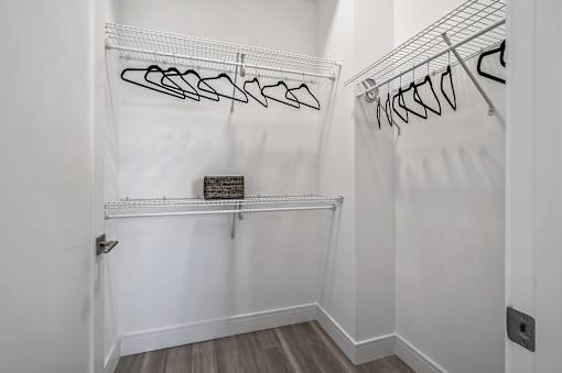 A white closet with clothes hanging on hangers.