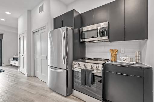 A modern kitchen with stainless steel appliances and black cabinets.