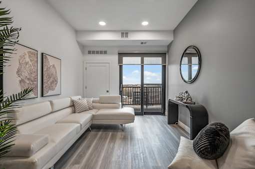 A modern living room with a white couch and a round mirror on the wall.
