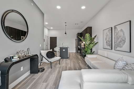 A modern living room with a white couch, a round mirror, and a wooden floor.
