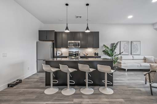 A modern kitchen with a bar stool set.