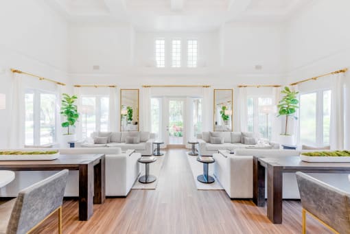 a living room with white couches and tables and windows