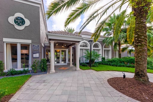 a building with a sidewalk and palm trees in front of it
