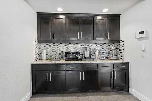 A kitchen with black cabinets and a black and white checkered backsplash.