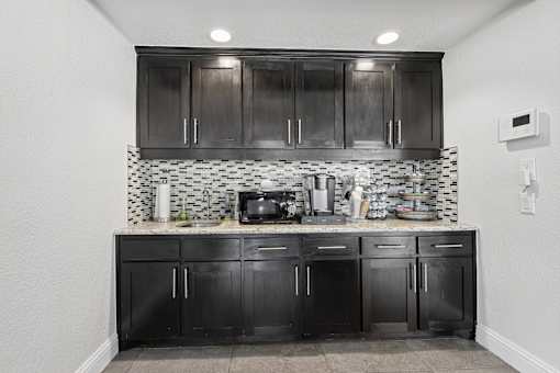 A kitchen with black cabinets and a black and white checkered backsplash.