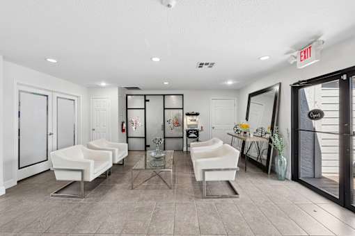 A spacious room with white chairs and a glass table.