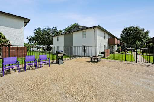 A park with purple benches and a black fence.