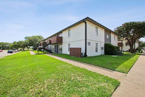 A white apartment building with a green lawn in front.