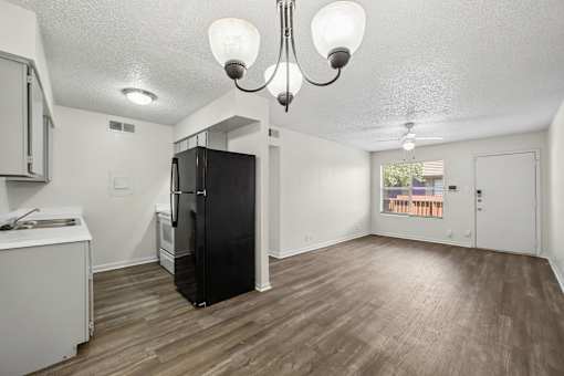 A kitchen with a black fridge and wooden floors.
