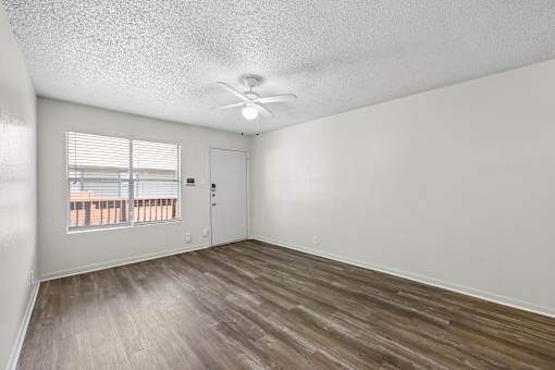 A room with a ceiling fan and a window with blinds.