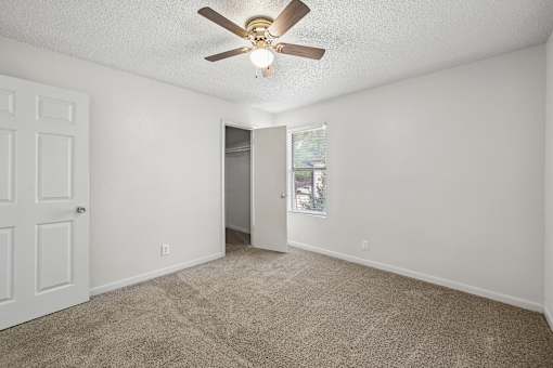 A room with a ceiling fan and carpeted floor.