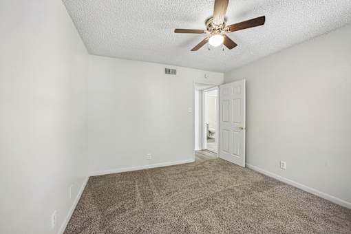 A room with a ceiling fan and carpeted floor.