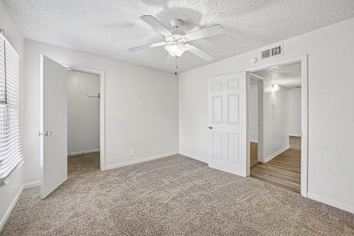 A room with a ceiling fan and carpeted floor.