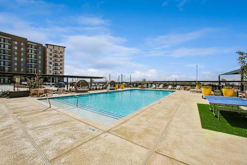 A large outdoor swimming pool surrounded by a concrete deck and a grassy area.