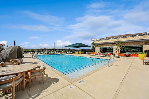 A large outdoor swimming pool with a sun lounger and a green umbrella.