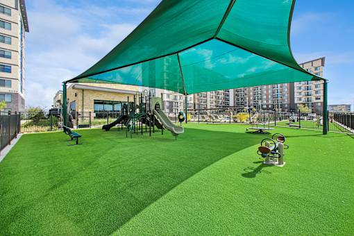 A playground with a green canopy and a slide.
