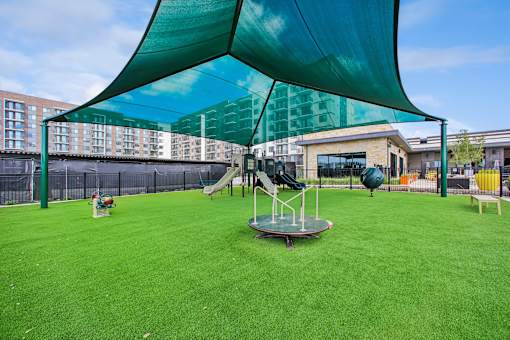 A playground with a green canopy and a slide.