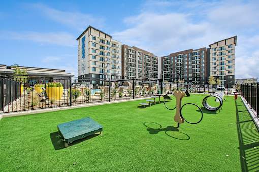 A playground with a green surface and a yellow trash can.