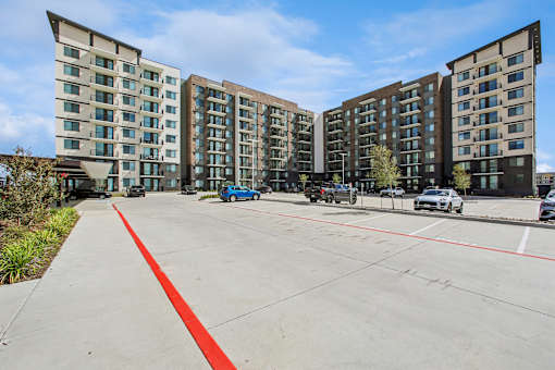 A parking lot in front of a multi-story apartment building.