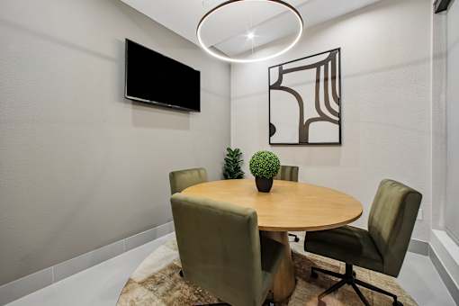 A conference room with a round table and chairs.