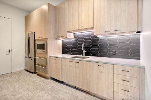 A kitchen with wooden cabinets and a black tile backsplash.