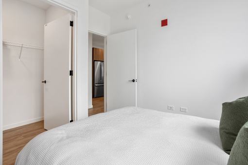 A white bed with a white mattress in a white room.