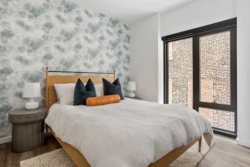 A bedroom with a large bed and a window with blinds.