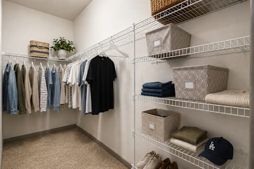 A room with a white wall and a shelf with clothes and boxes.