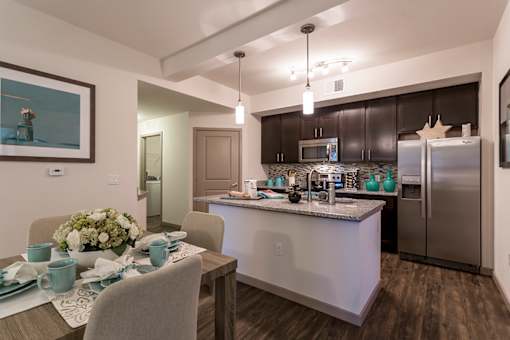 A modern kitchen with a dining table set for two.