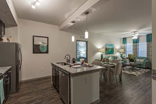 A modern kitchen with dark wood floors and stainless steel appliances.