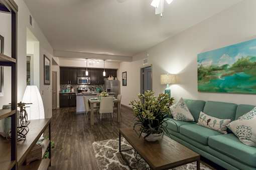 A living room with a green couch and a painting on the wall.