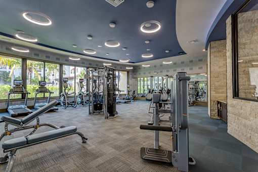 A gym with a variety of equipment including treadmills, weights, and exercise machines.