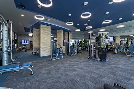 A gym with a variety of equipment and a grey carpet.