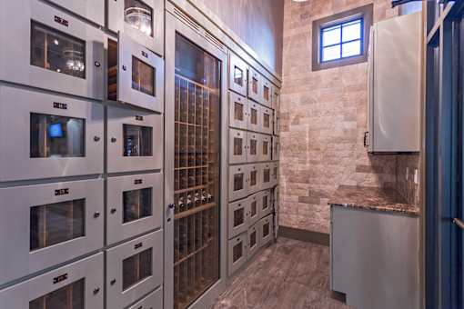 A row of stainless steel ovens are lined up in a kitchen.