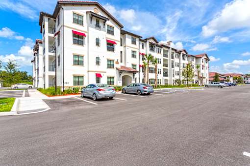 A row of apartment buildings with cars parked in front.