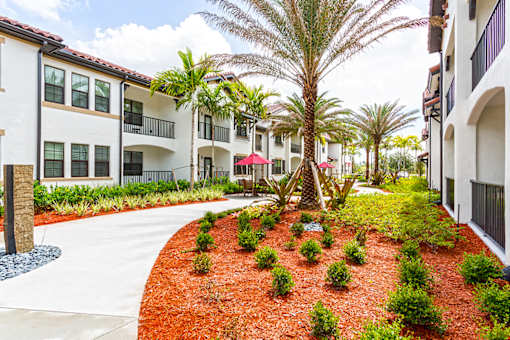 A red mulched garden in front of a white building.